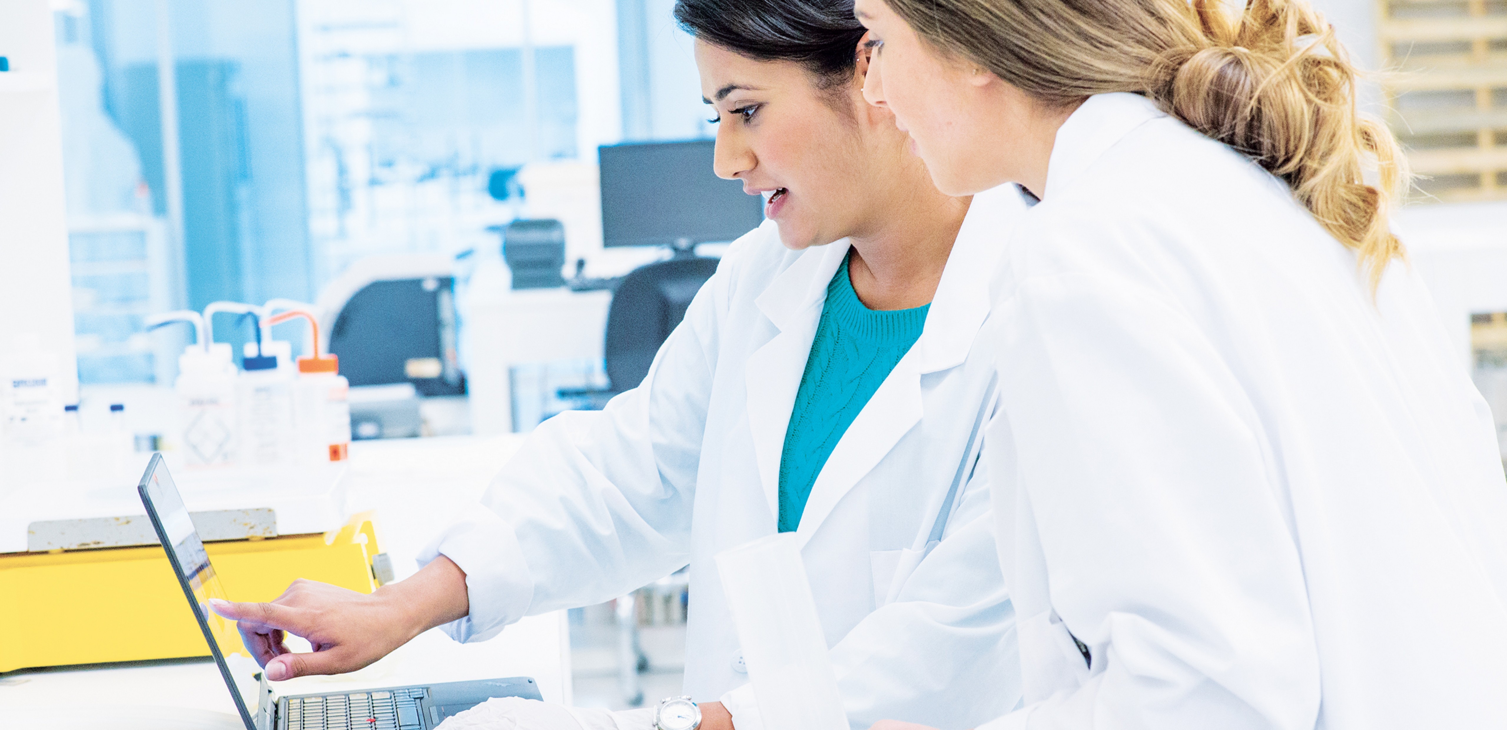 Two women healthcare workers, working on a Windows PC in a lab.