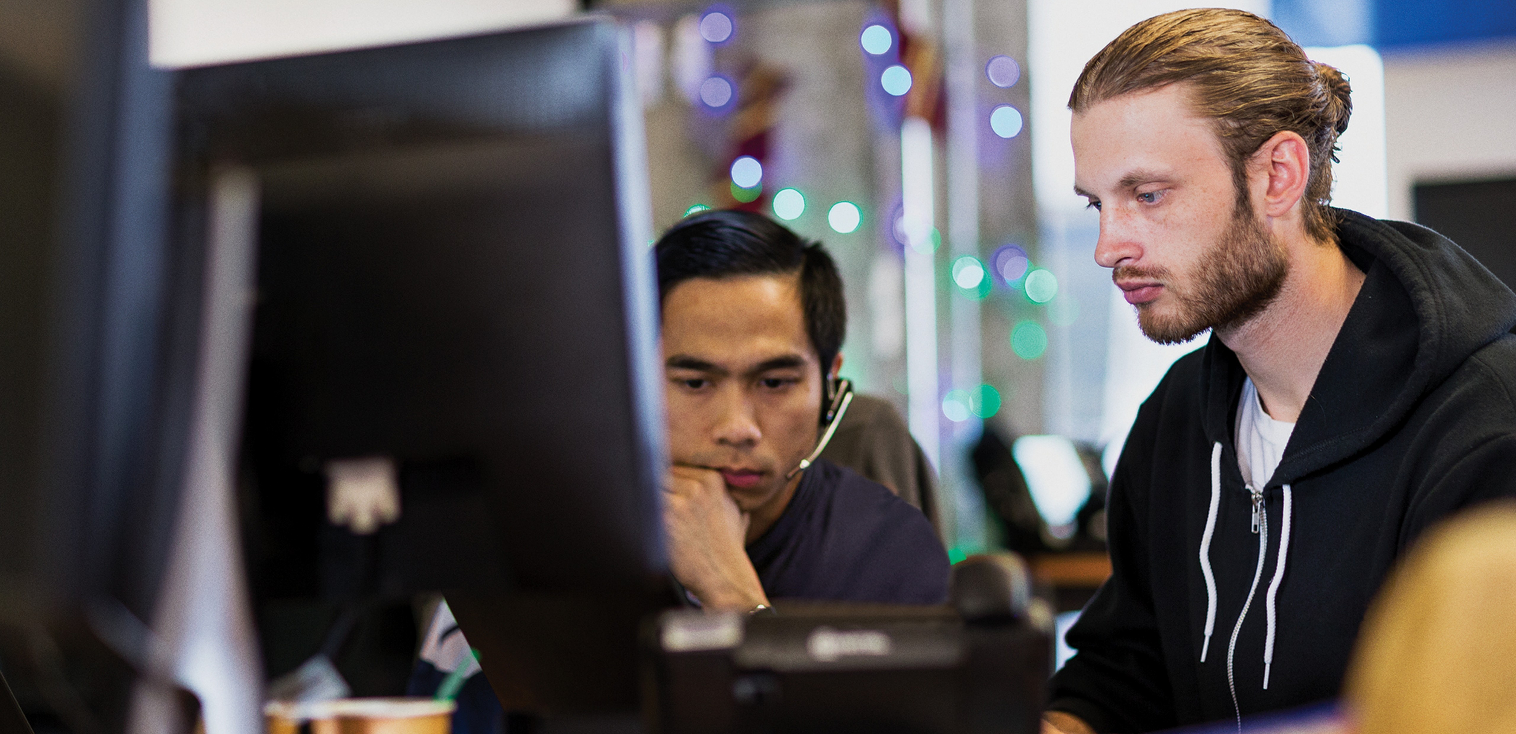 Two men sitting at a desk working on a computer.
