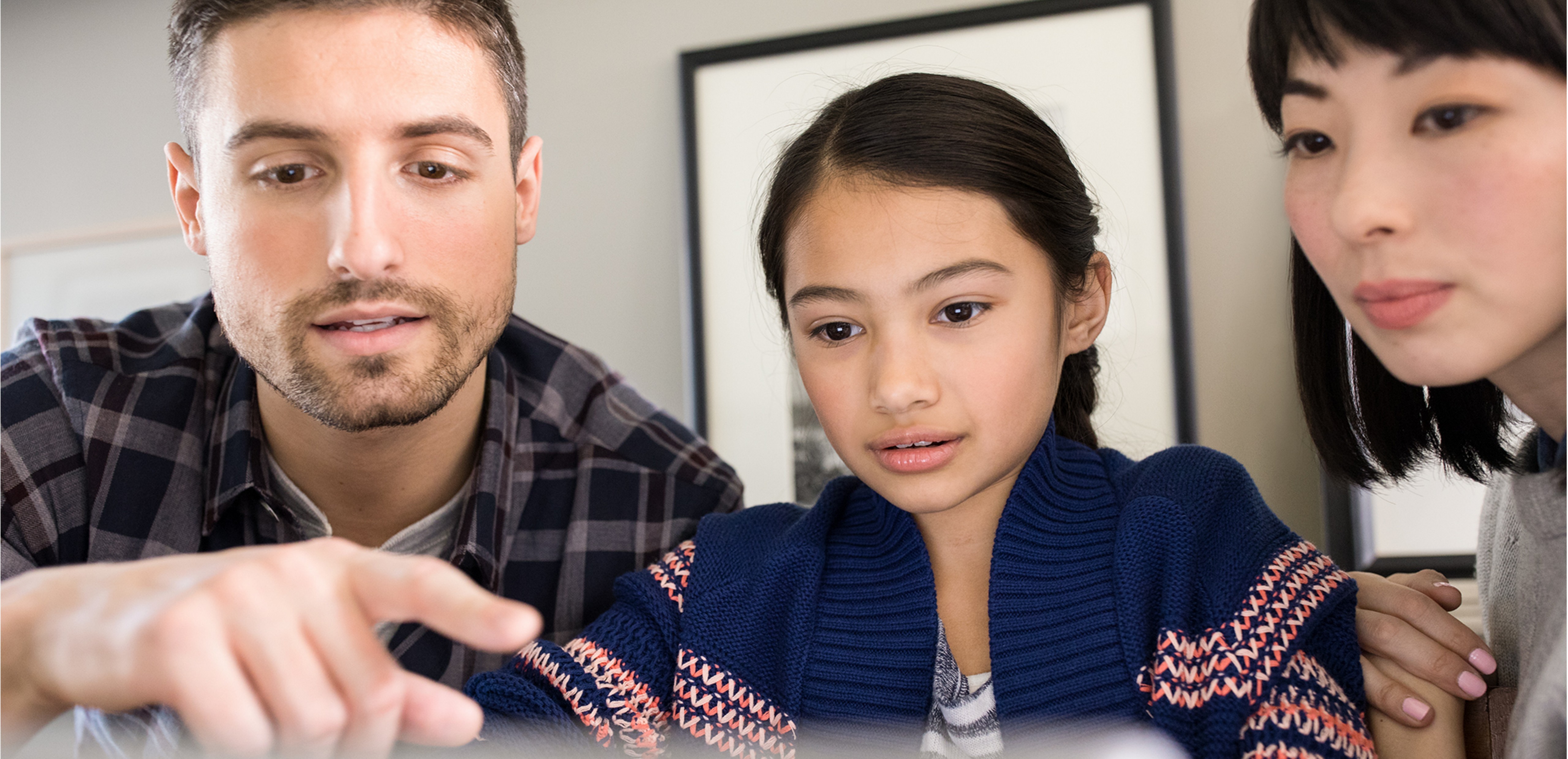 Man, woman and child sitting together looking at a computer screen.