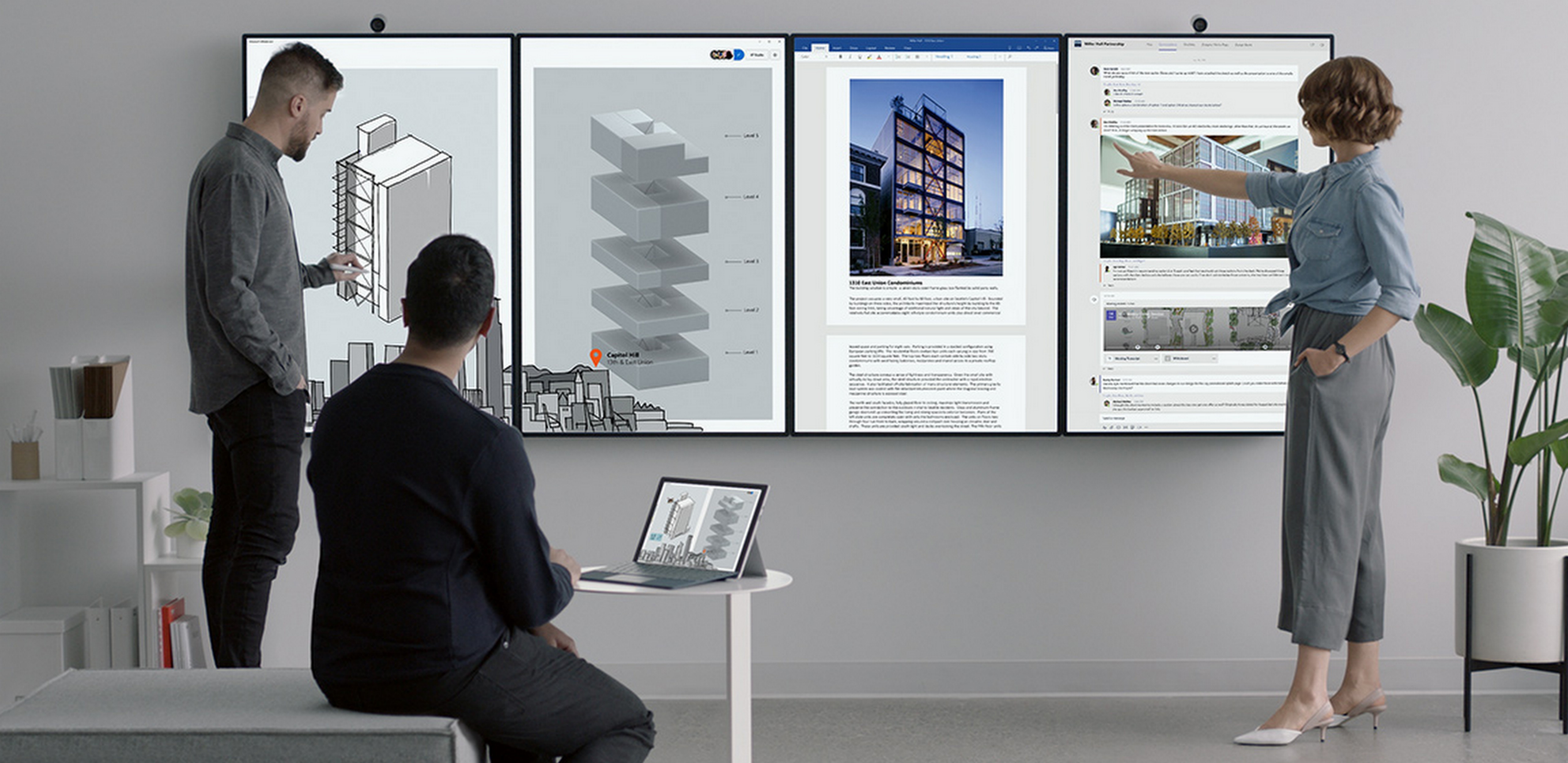 Three people working with four Surface Hub 2 displays