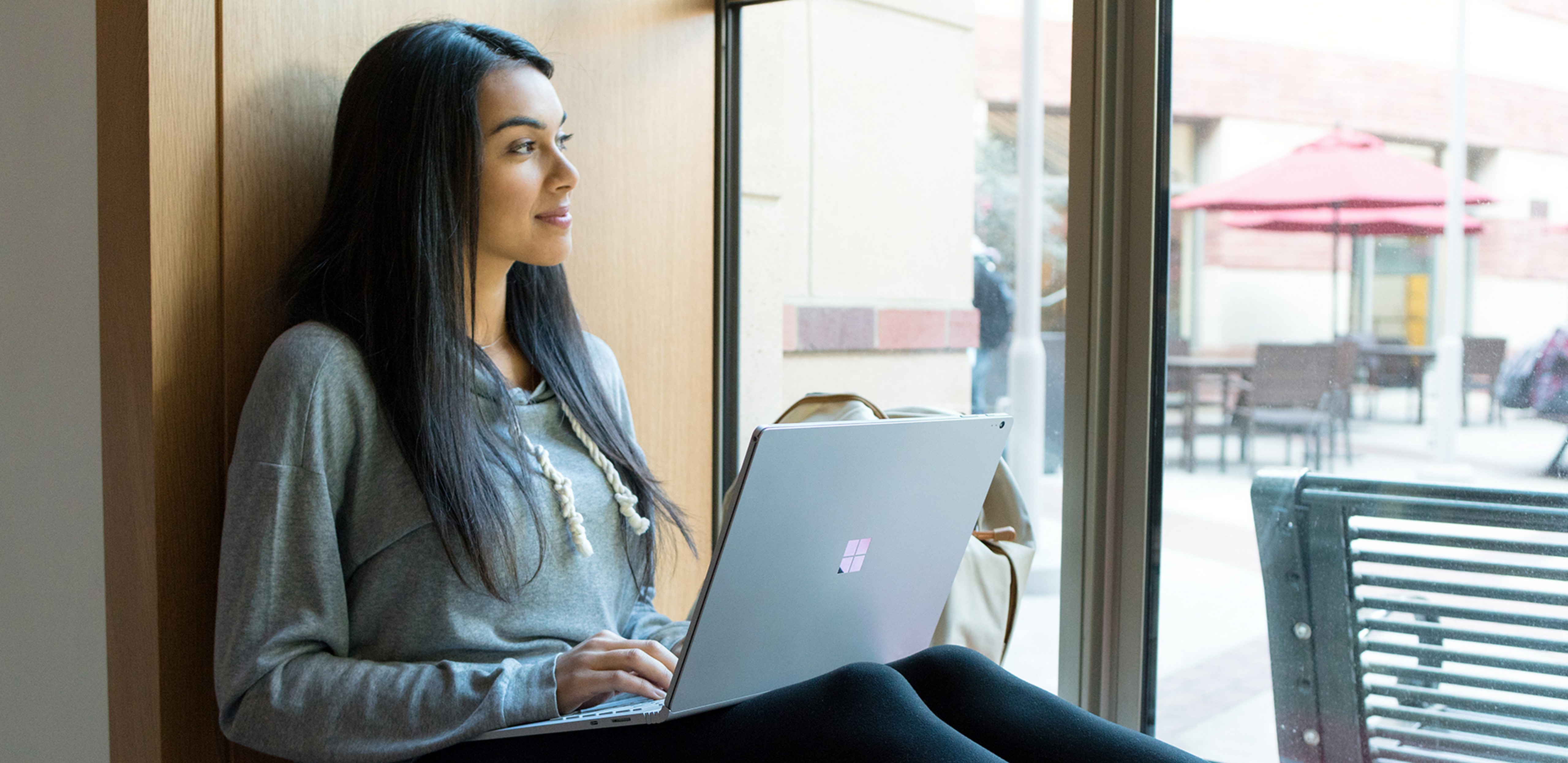 Person sitting by a window, using a Surface device