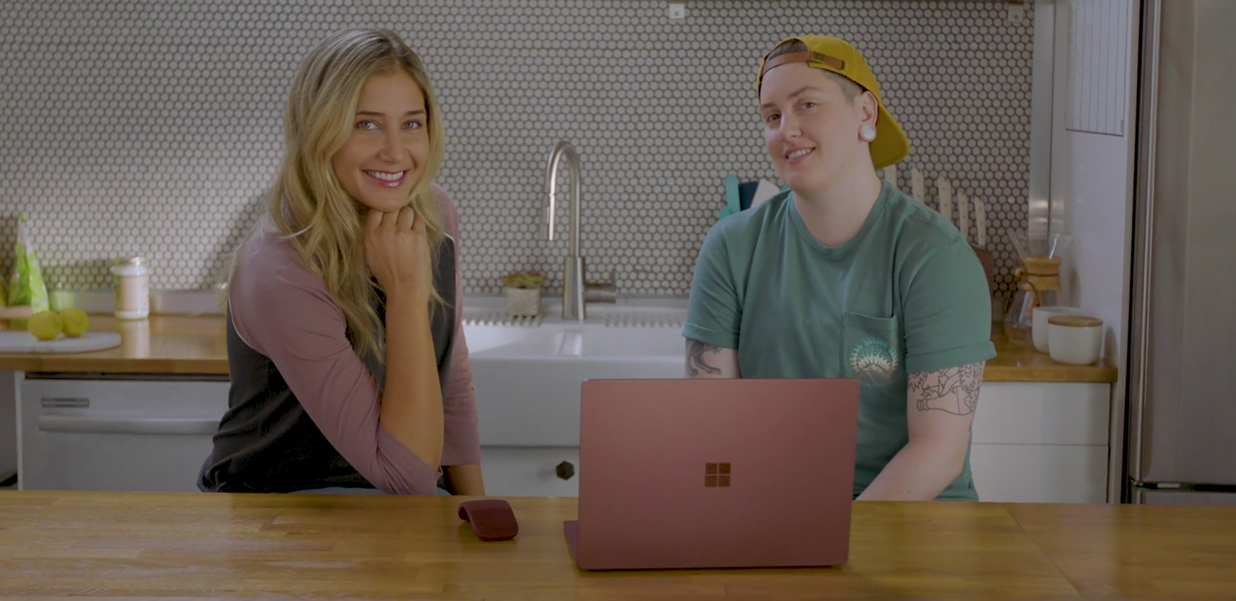 Two women sitting in a kitchen in front of a Microsoft Surface