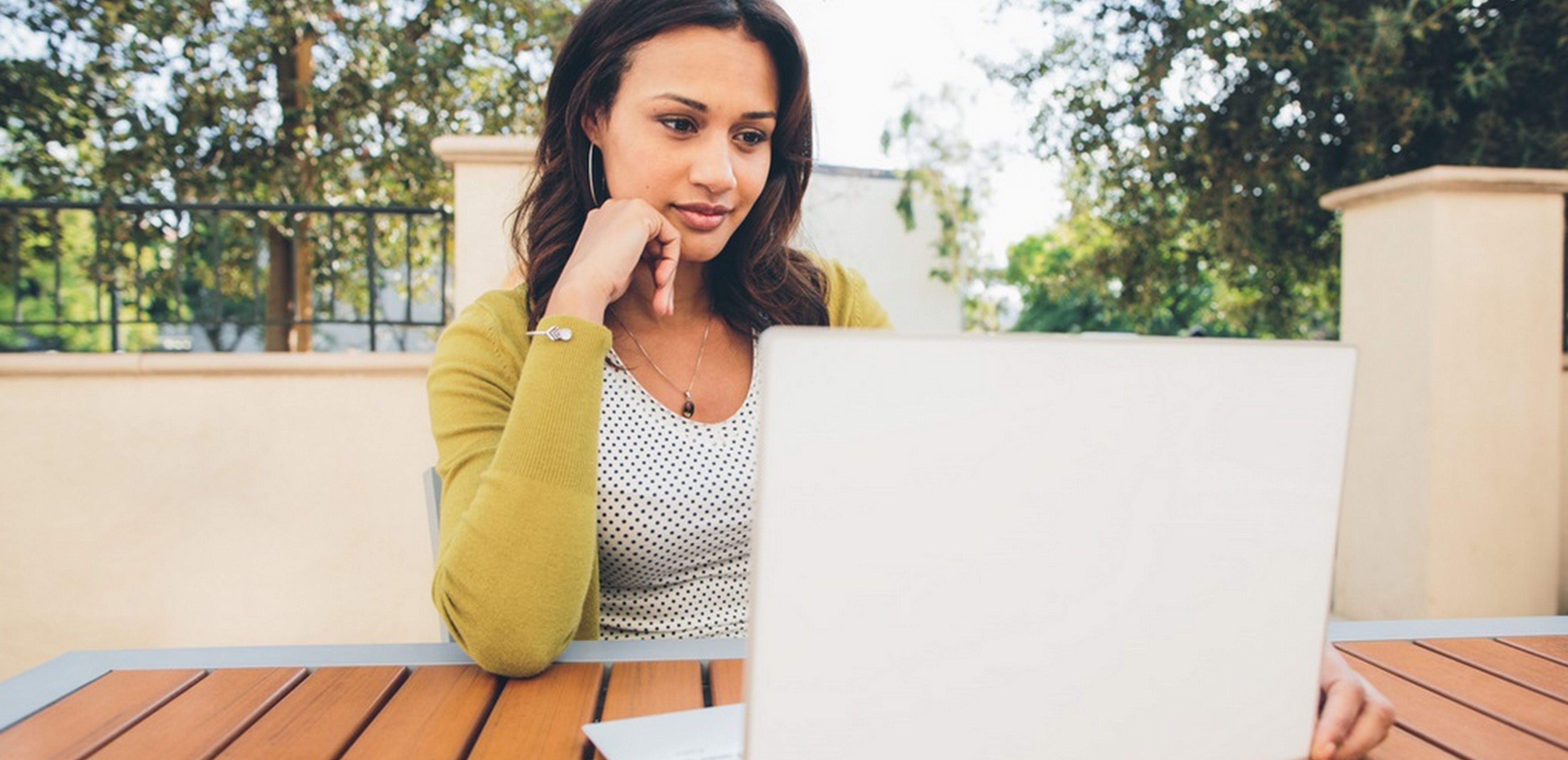 Woman sitting at a table outside working on a Windows 10 laptop.