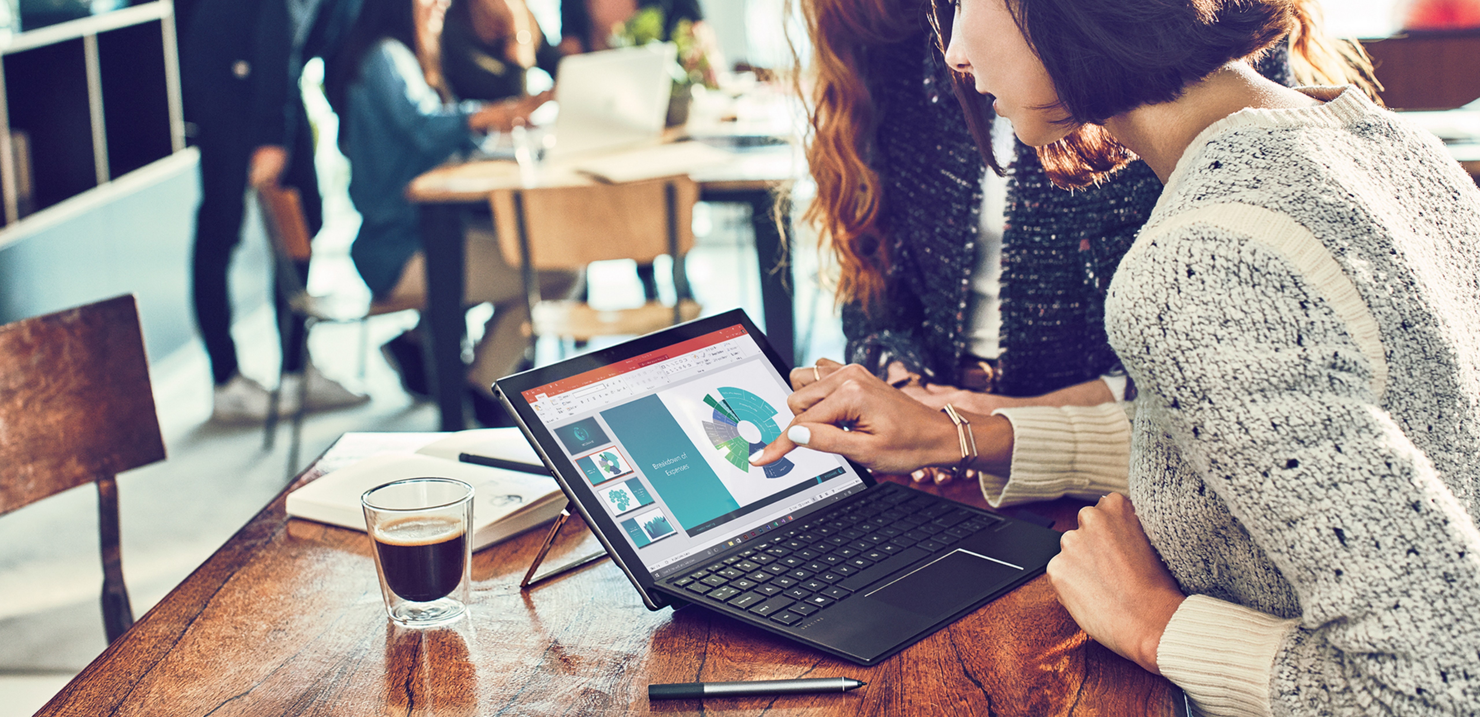 Two women sitting at a desk working on a Windows 10 PC.
