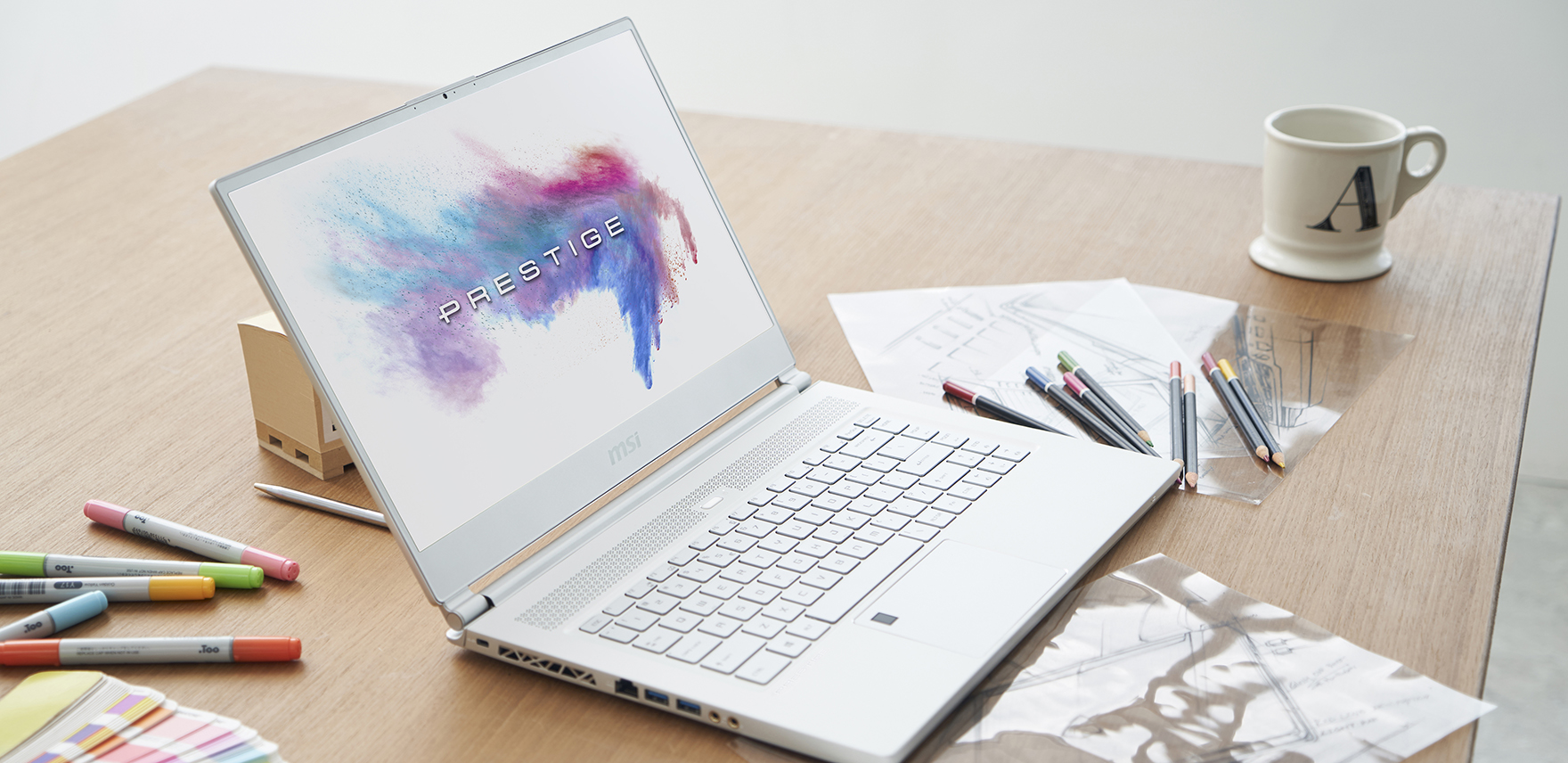 MSI P65 Creator on a desk with pens, markers, papers and a mug