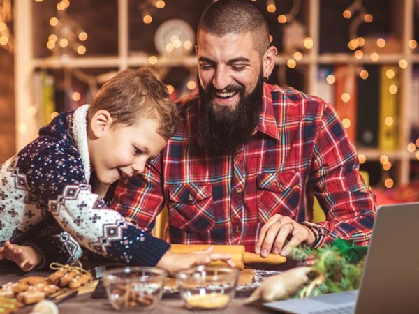 Father and son prepare a holiday meal assisted by a laptop computer
