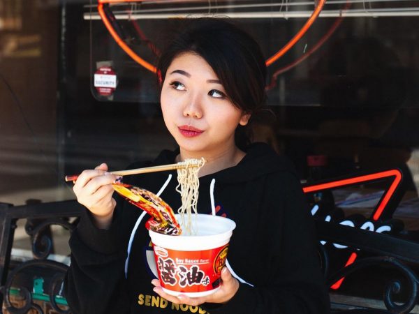 A woman stands eating food outside