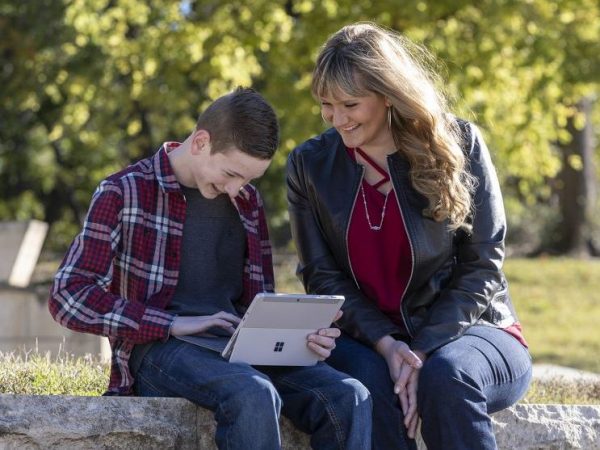A child using a tablet with their mother sitting next to them