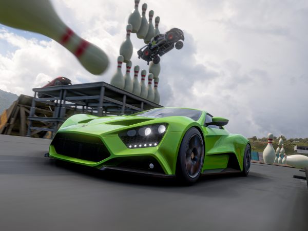 Race car driving through huge falling bowling pins