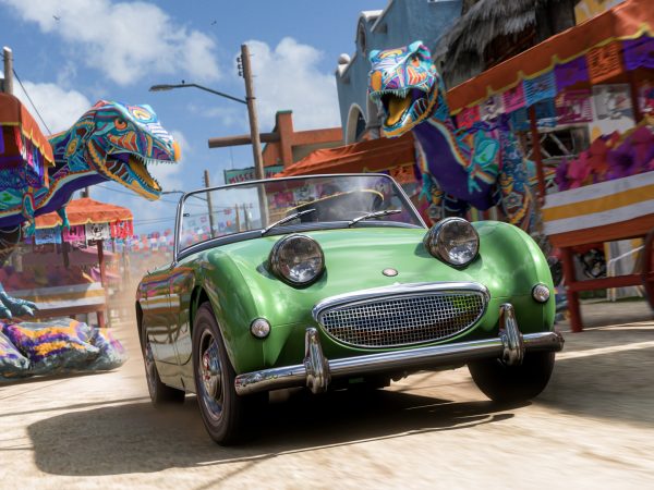 Racing car drives through a street of a Mexican city adorned with decorations