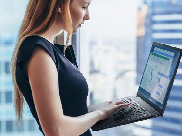 Woman holding a laptop next to an office window