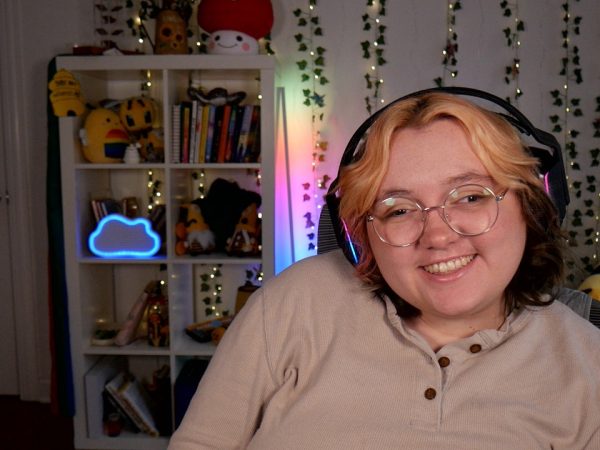 Woman in glasses smiling at camera, wearing headphones