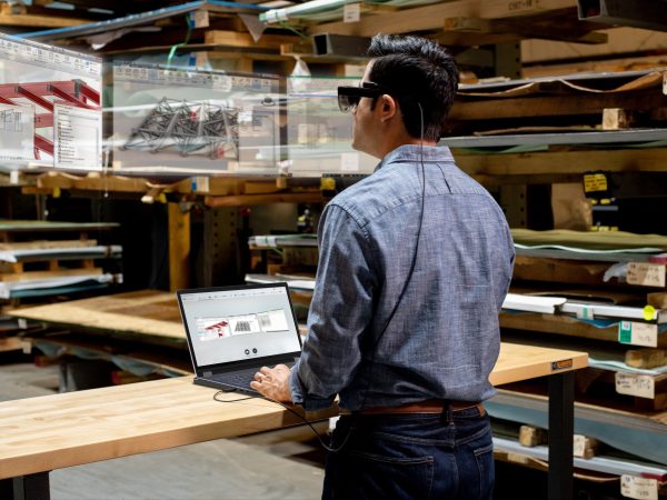 Man wearing headset viewing virtual screens above laptop