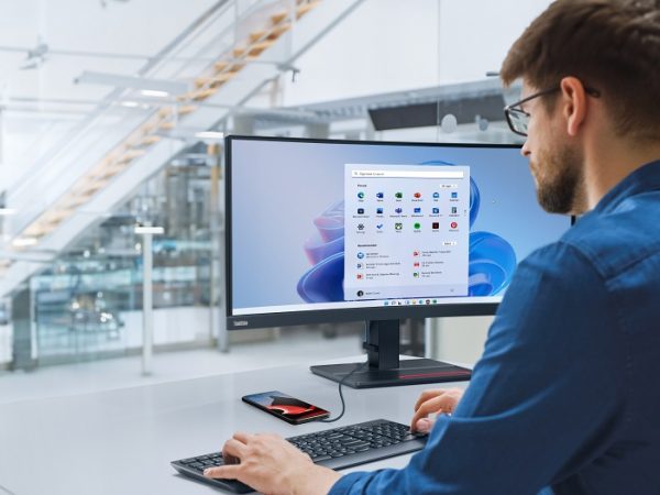 Man typing on keyboard in front of monitor with phone plugged into monitor