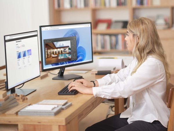 Woman working at a desktop computer with two monitors