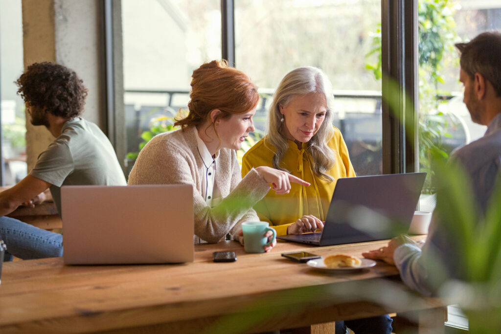 Four people in an office working on laptop devices. Four people in an office working on laptop devices.