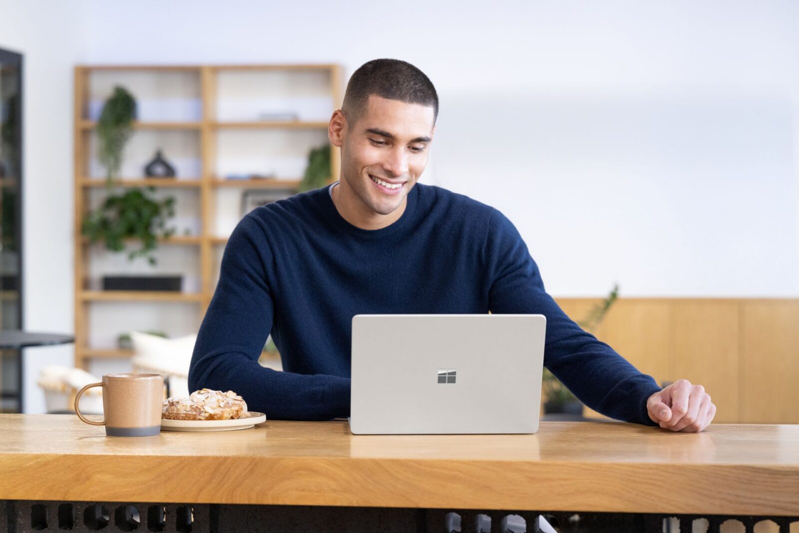 A person using a Surface Laptop running Windows 11 at a cafe table