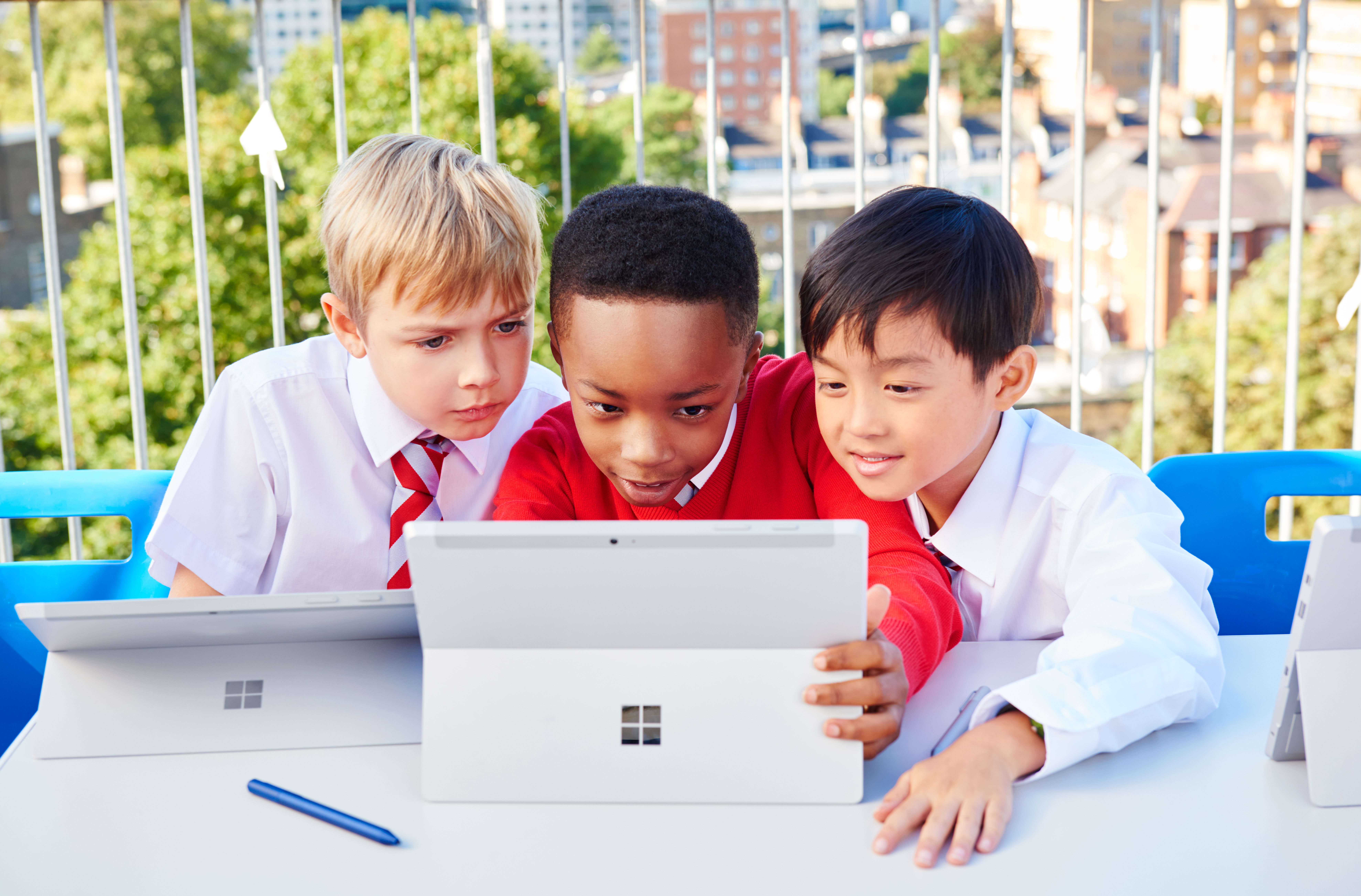 Three young students playing and working with Surface 3.