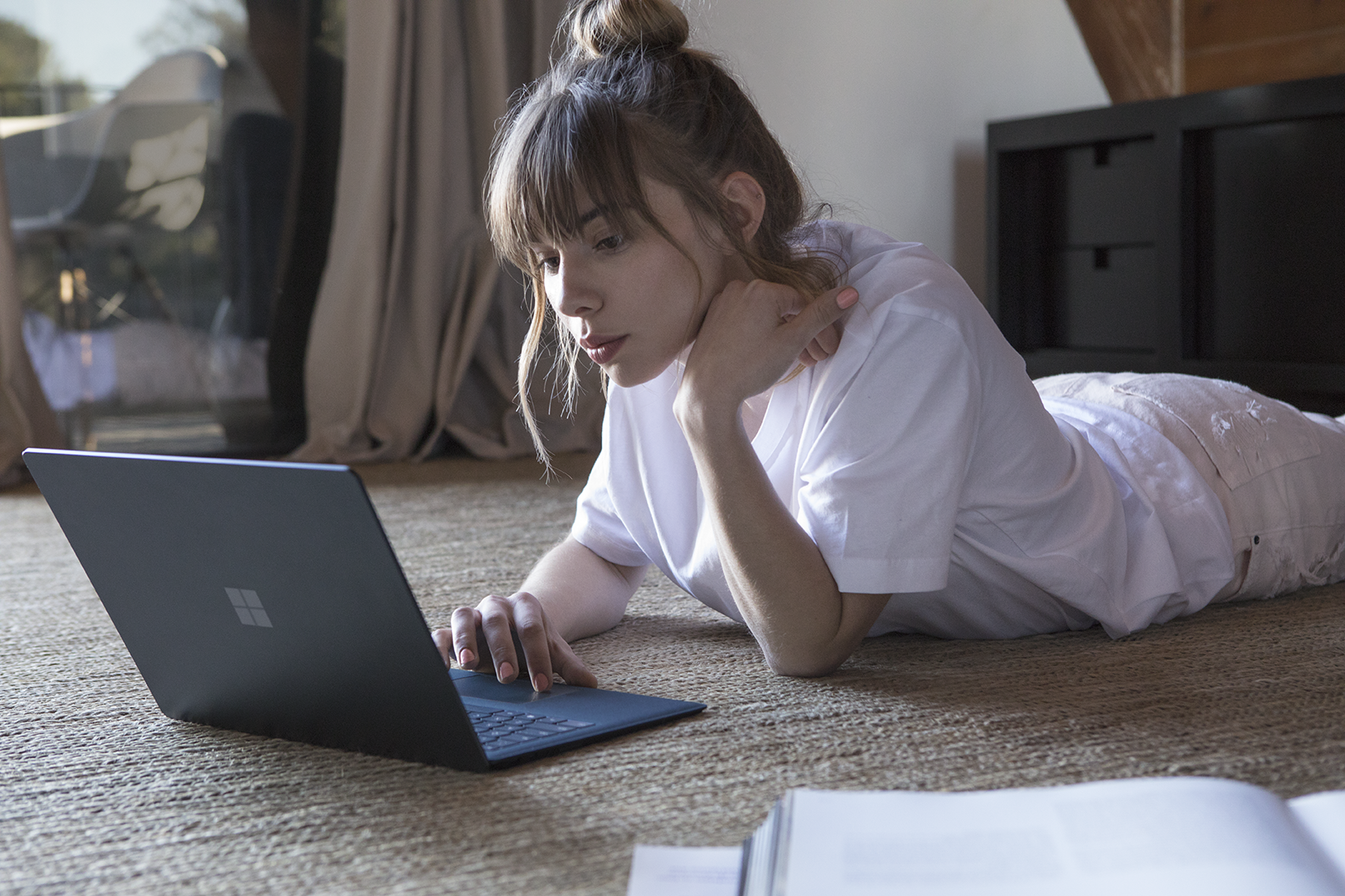 Woman laying down working on Microsoft Surface Laptop in Cobalt Blue