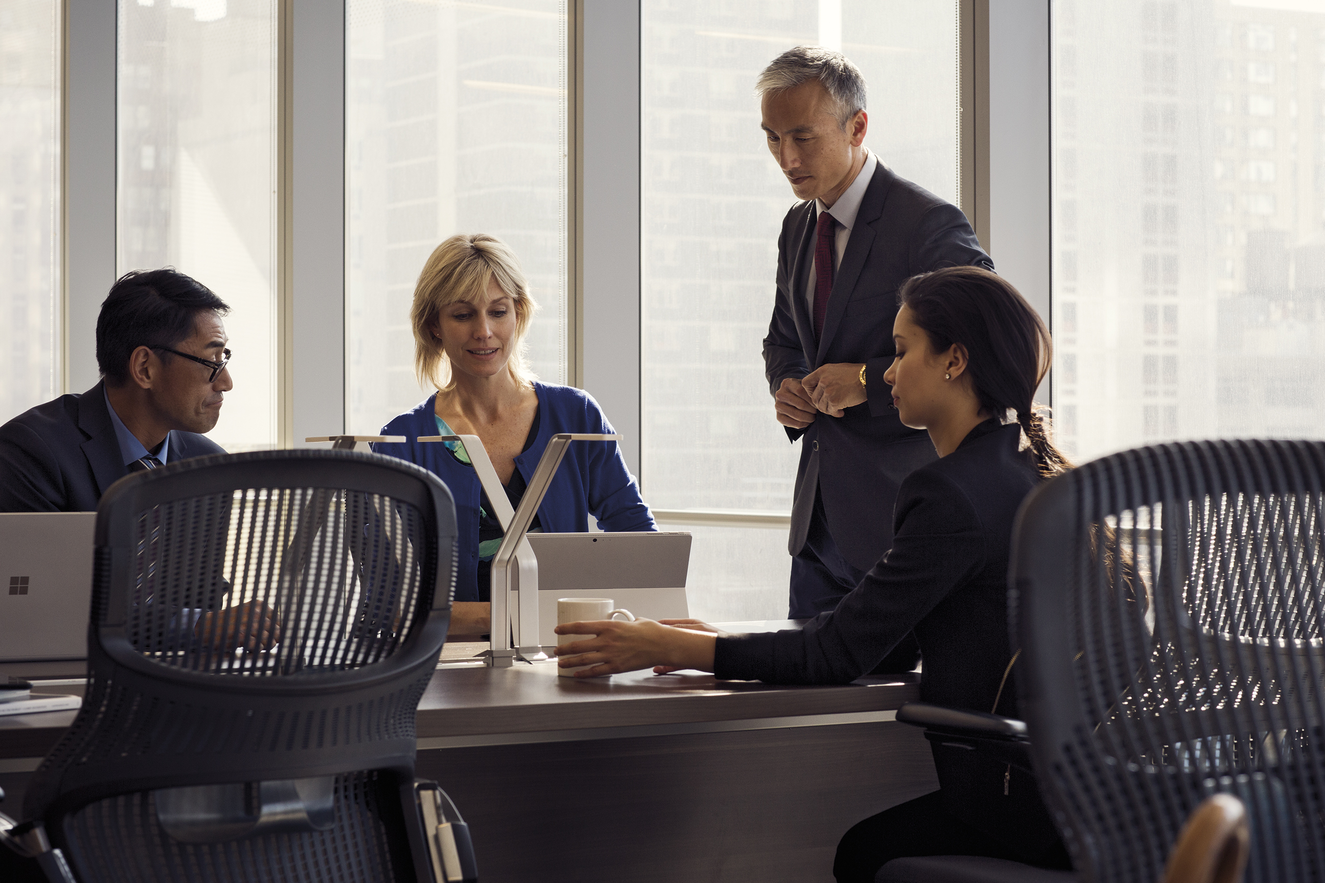 Men and woman sitting around a conference table looking at a Surface Pro.