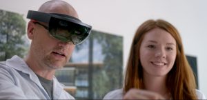 Man wearing Microsoft HoloLens standing next to woman.