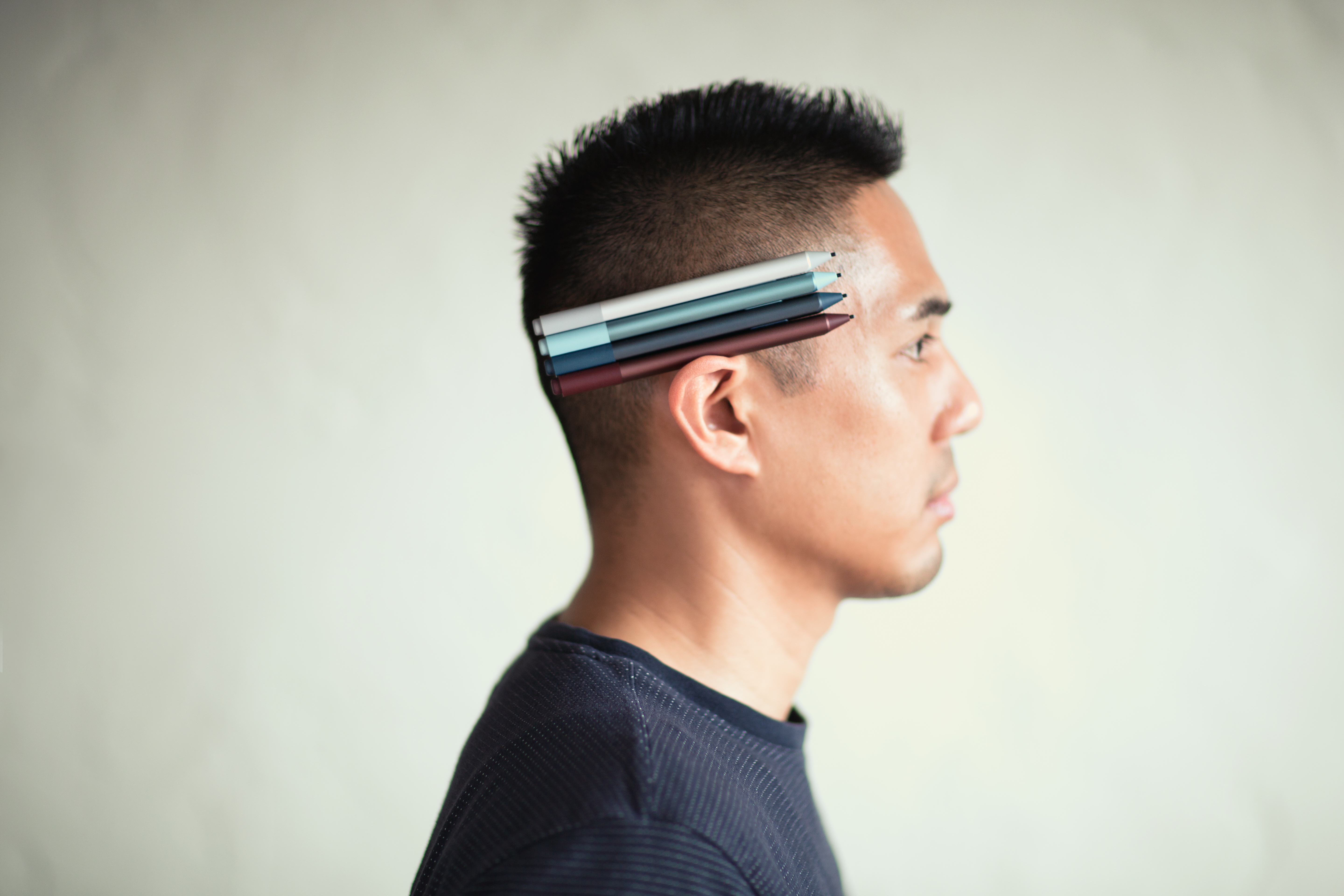 Profile shot of a man standing to the side with four Surface Pens in his ear.