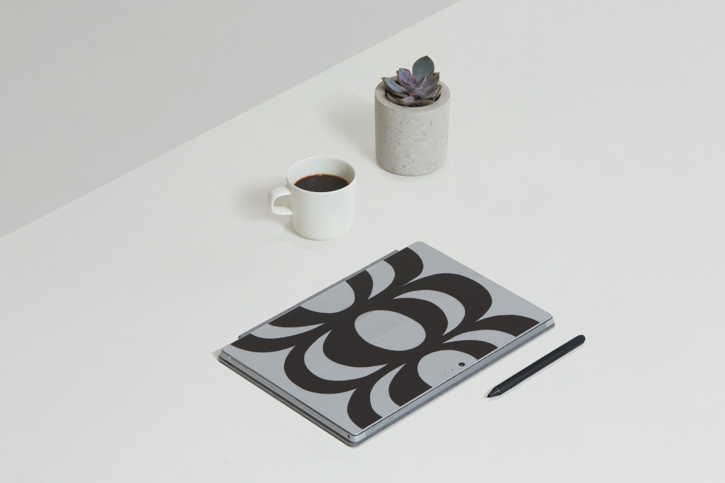 Surface Pro with a Marimekko accessory on a table with a cup off coffee and a plant.