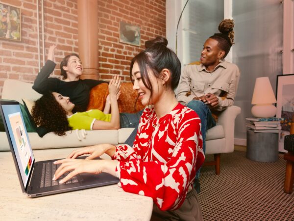 Four friends relaxing on couches, one interacting with a laptop computer.