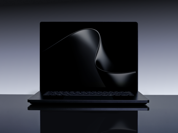 A laptop computer displaying a black graphic resembling a wave against a dark background.